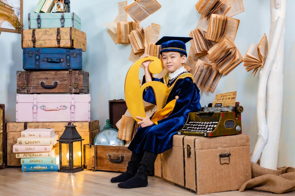 boy holding a large number six next to a vintage typewriter