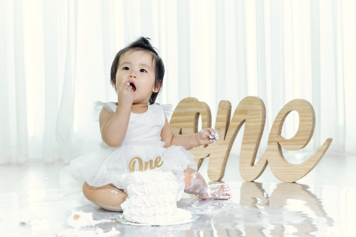 cake smash shoot showing a joyful baby with frosting on their face