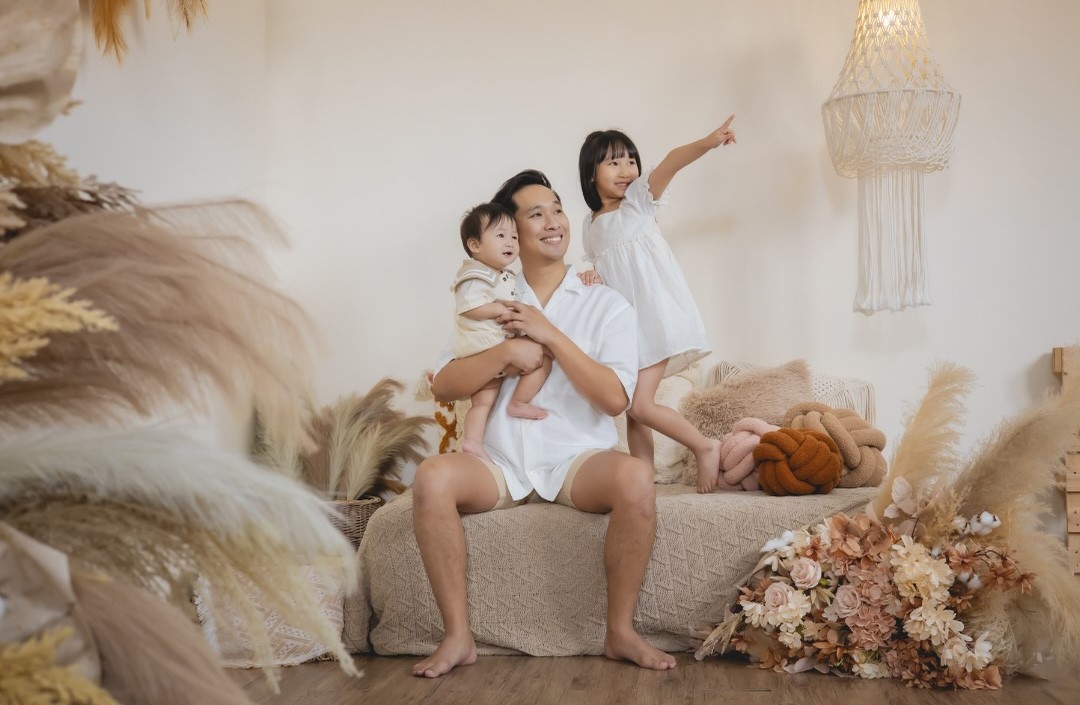 A father and his children posing for a picture surrounded by flowers.