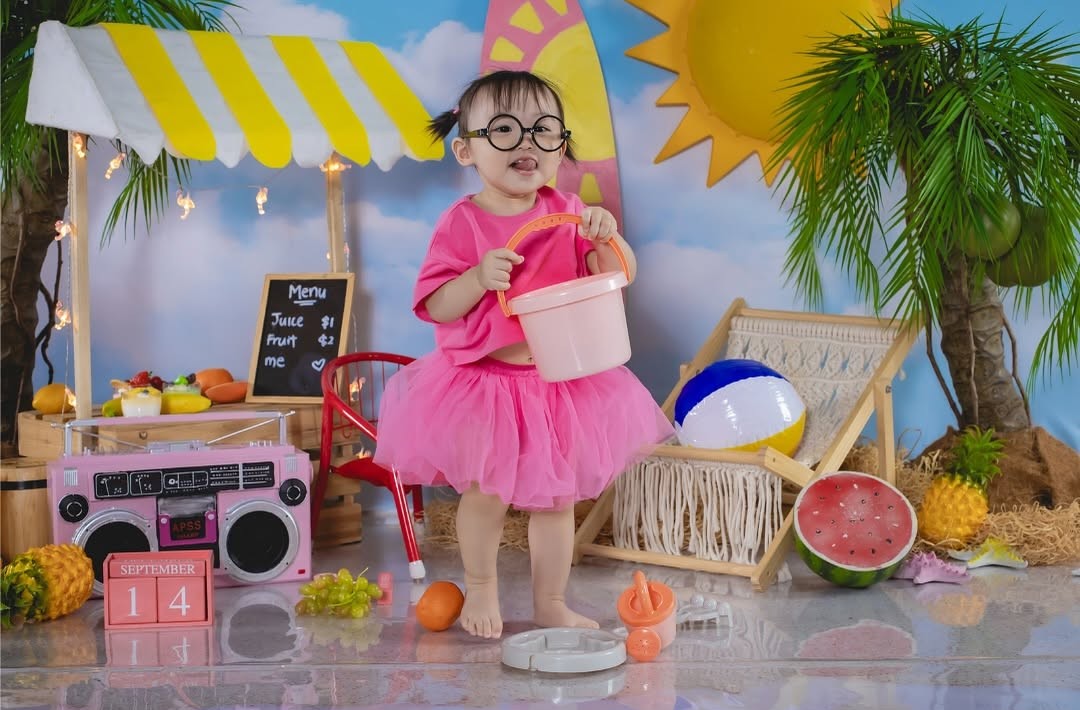 Baby holding a bucket with having a background of a beach with sunny sun.