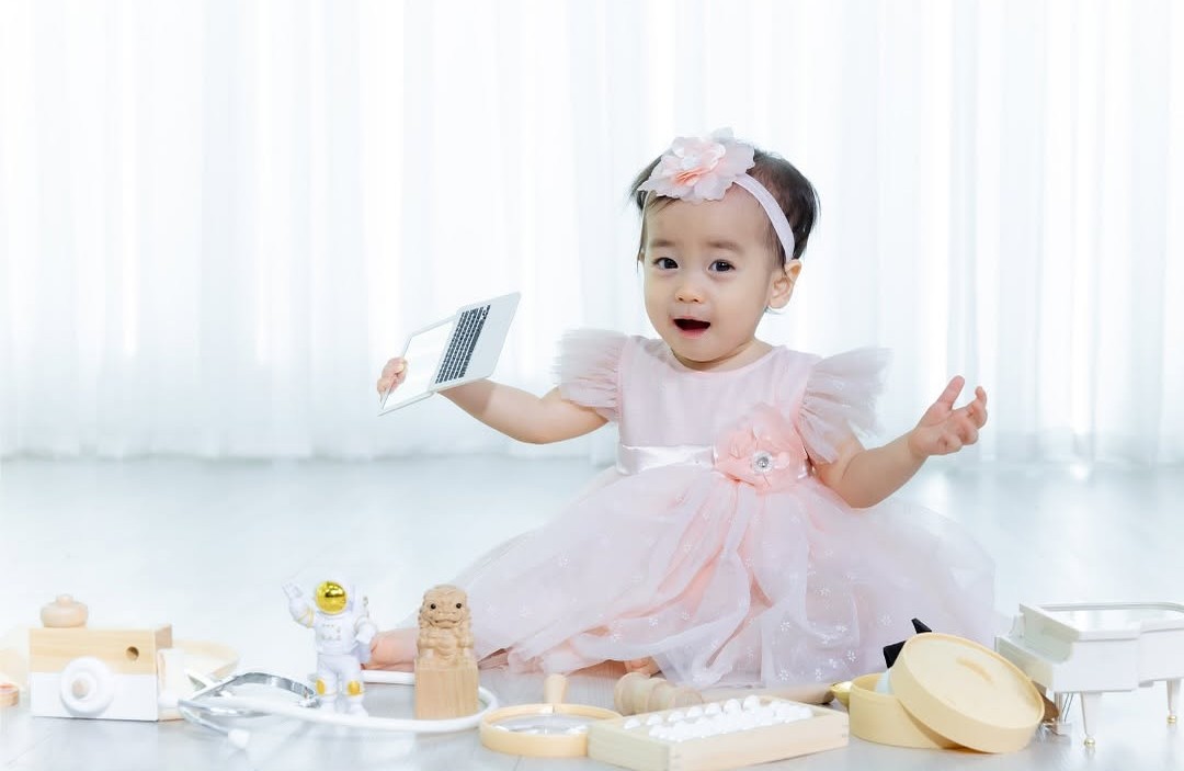 Baby girl playing with wooden toys while sitting on the floor.