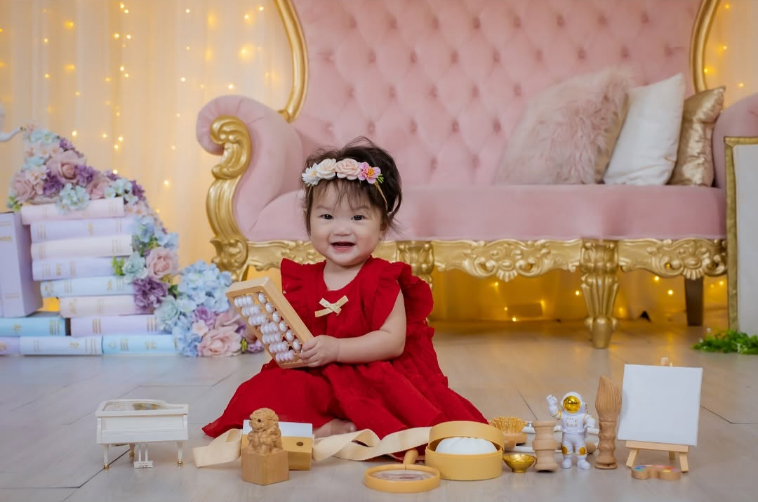a baby girl in red dress holding an abacus
