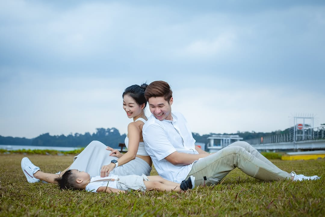 little boy laying down on grass with parents