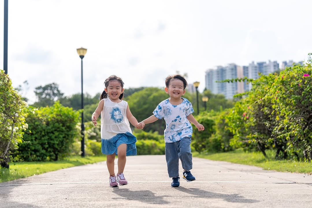 a little boy and girl running happily while holding hands