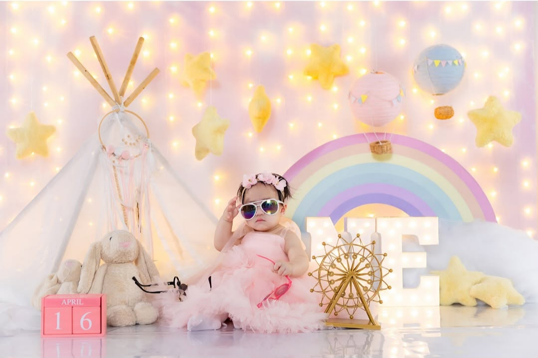 a baby girl dressed in pink and has a sunglasses on while sitting on the floor