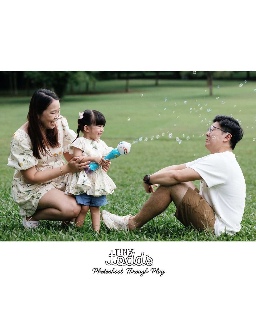 little girl playing with bubbles with her parents outside